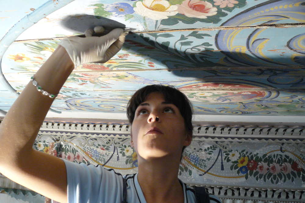 An artisan works to restore one of the hotel's painted ceilings