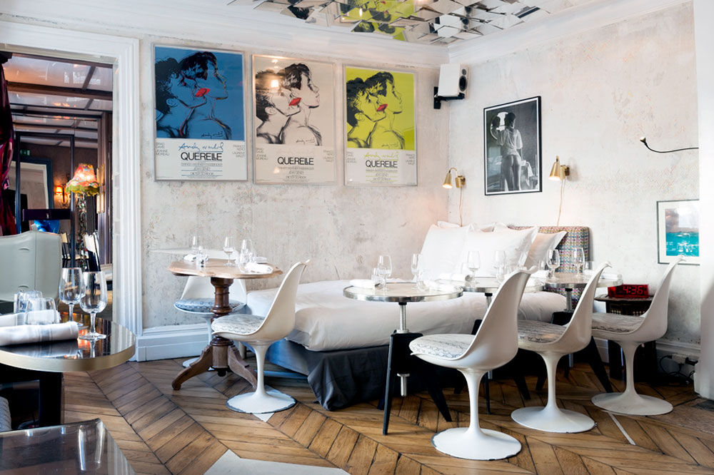 Dining room seating at a fully made bed at Derrière in Paris, France - Derrière