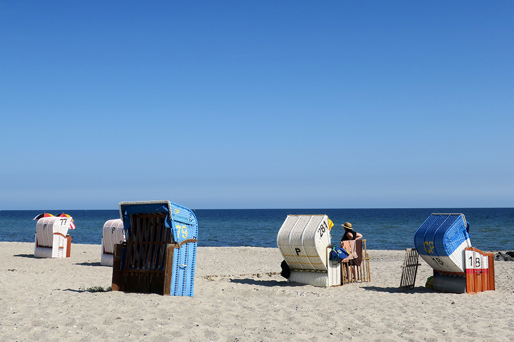<em>Strandkörbe</em>, which are hooded basket-like chairs, lined up on the beach in Hohwacht, Germany - Photo by Hideaway Report editor